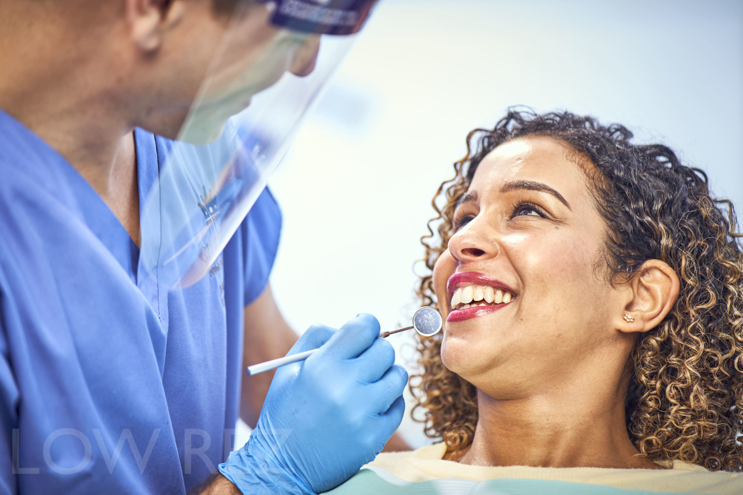 Dental professional examining a patient during a consultation with a dental mirror.