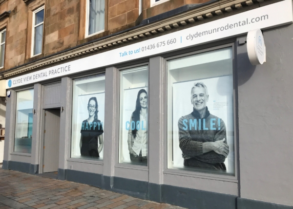 Exterior view of Clyde View Dental Practice with three large window displays featuring smiling individuals.