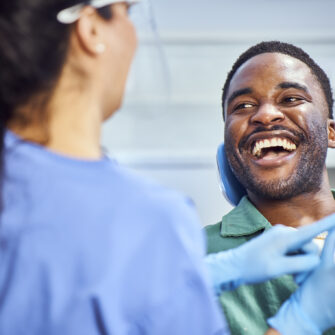 A patient smiling while interacting with a dental professional in a clinical setting.
