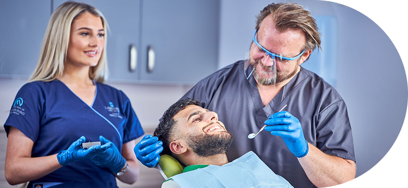 A dentist examining a patient in a dental clinic with a dental assistant present.