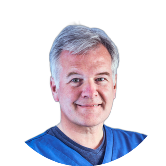 Portrait of Duncan Black wearing blue scrubs with a friendly expression, head and shoulders cropped against a light background