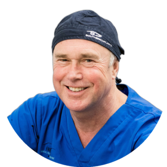 Portrait of Duncan Robertson, a dentist, wearing blue scrubs and a navy cap, smiling for a professional headshot suitable for Clyde Munro Dental