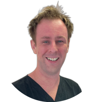 Tom Lewis, a dental clinician, wearing black scrubs and smiling for Clyde Munro Dental team portrait