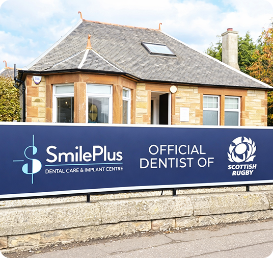 SmilePlus Dental Care & Implant Centre banner reads Official Dentist of Scottish Rugby on a blue sign affixed to a stone building with a slate roof