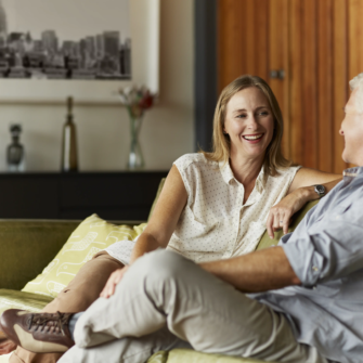 A smiling woman talks with a grey-haired man on a sofa, alongside guidance on Denplan Care and regular dental assessments.
